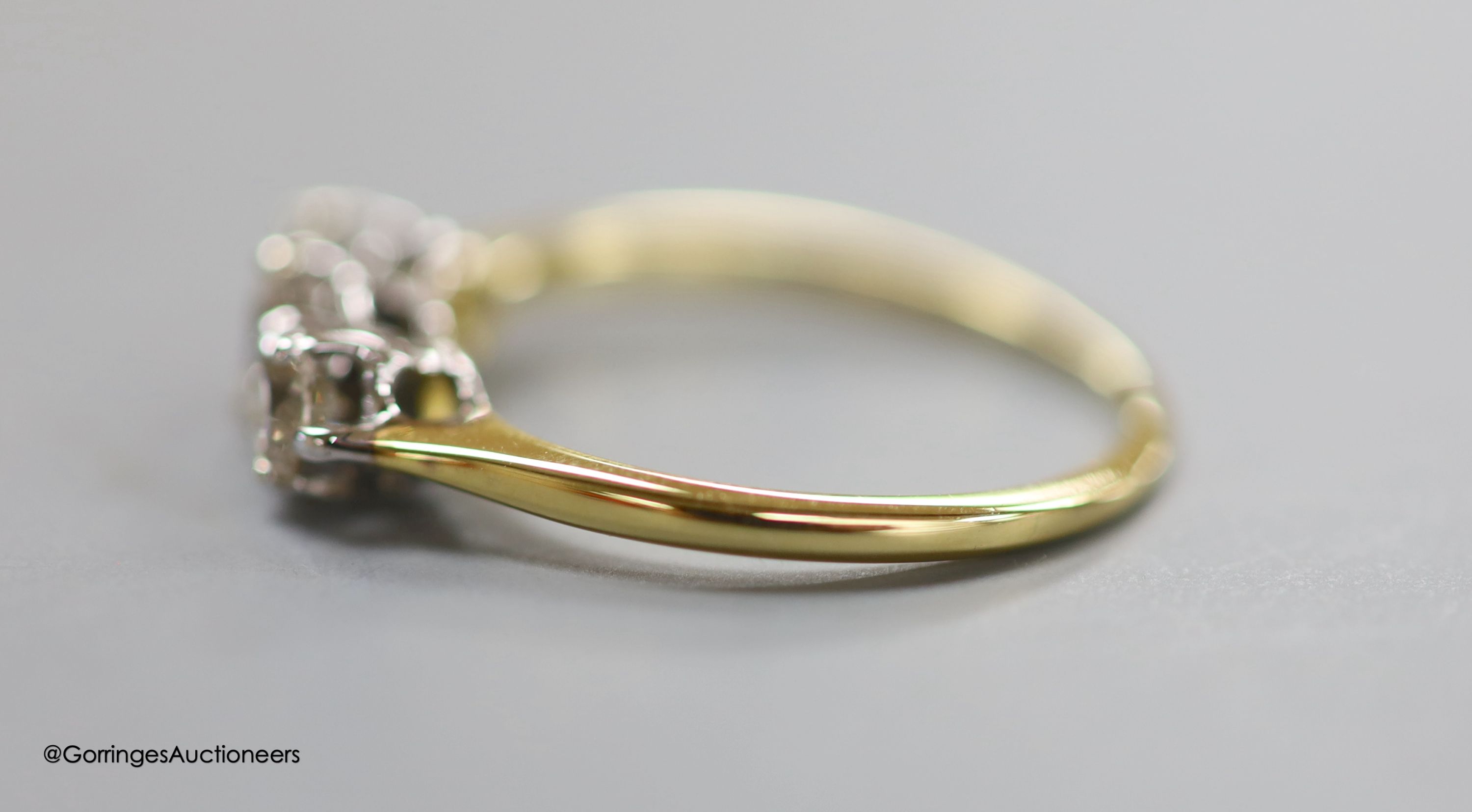 An 18ct and three stone diamond ring, size LM, gross 2.1 grams.
